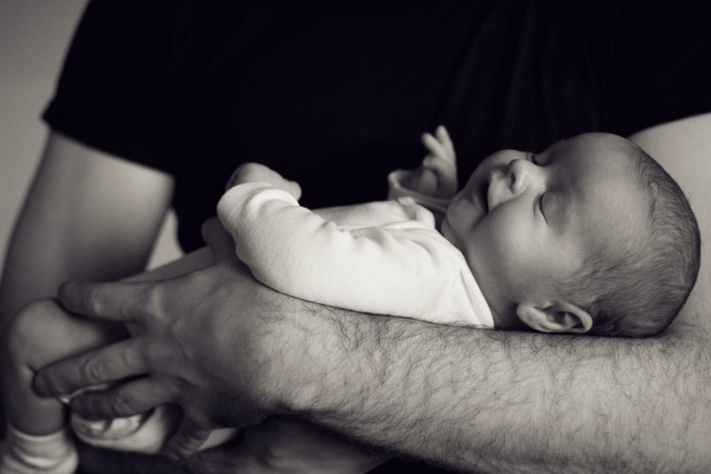 black and white image of man holding newborn baby.