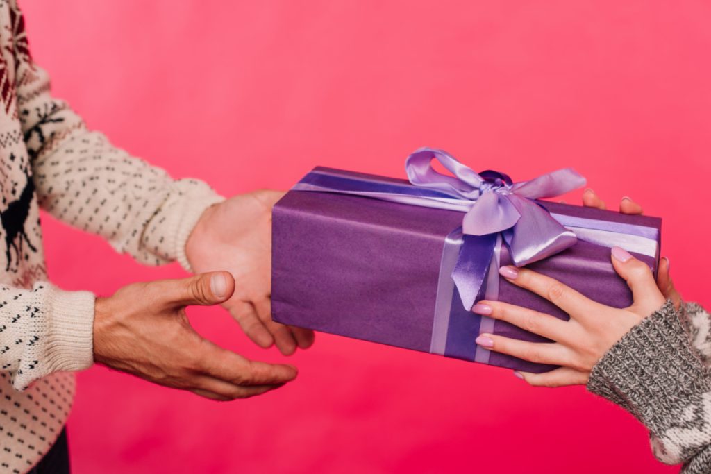 woman handing purple gift box to man.