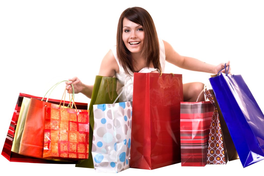 smiling woman holding many colorful gift bags