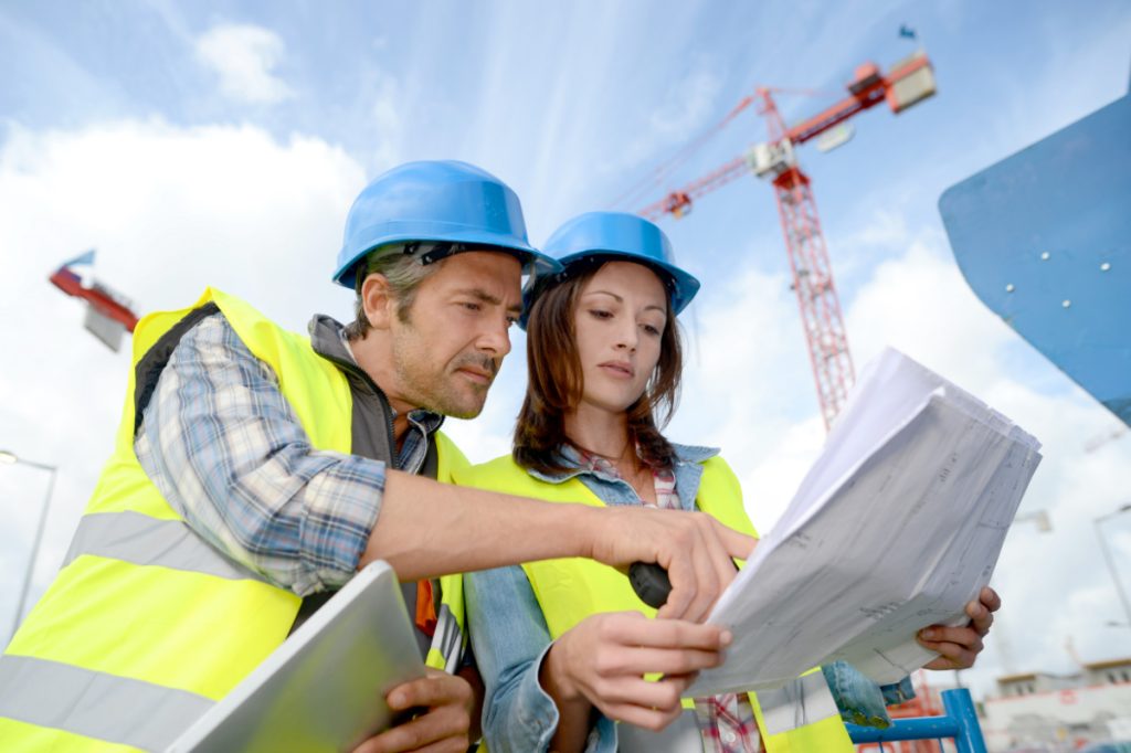 male and female construction workers looking at plans.