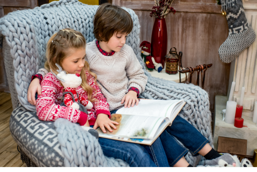 young boy and girl in large chair reading book together.