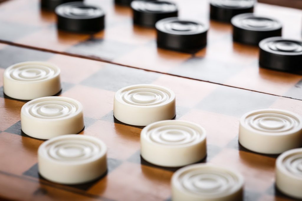 White and black checkers on a wooden board.