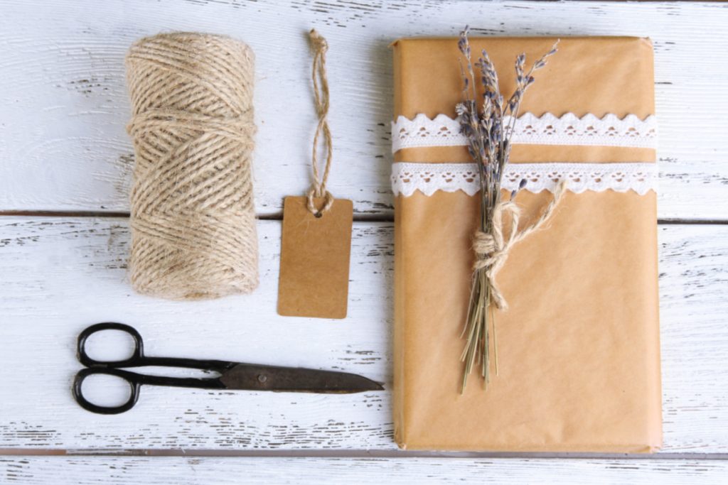 A brown wrapping paper, scissors and a gift tag on a wooden table.